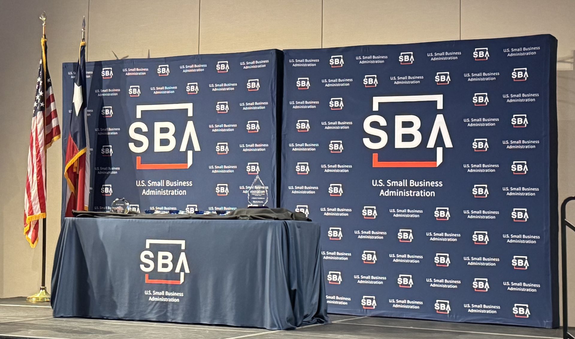 Stage setup at the 2025 SBA Awards Ceremony, featuring U.S. Small Business Administration banners, flags, and award display table.